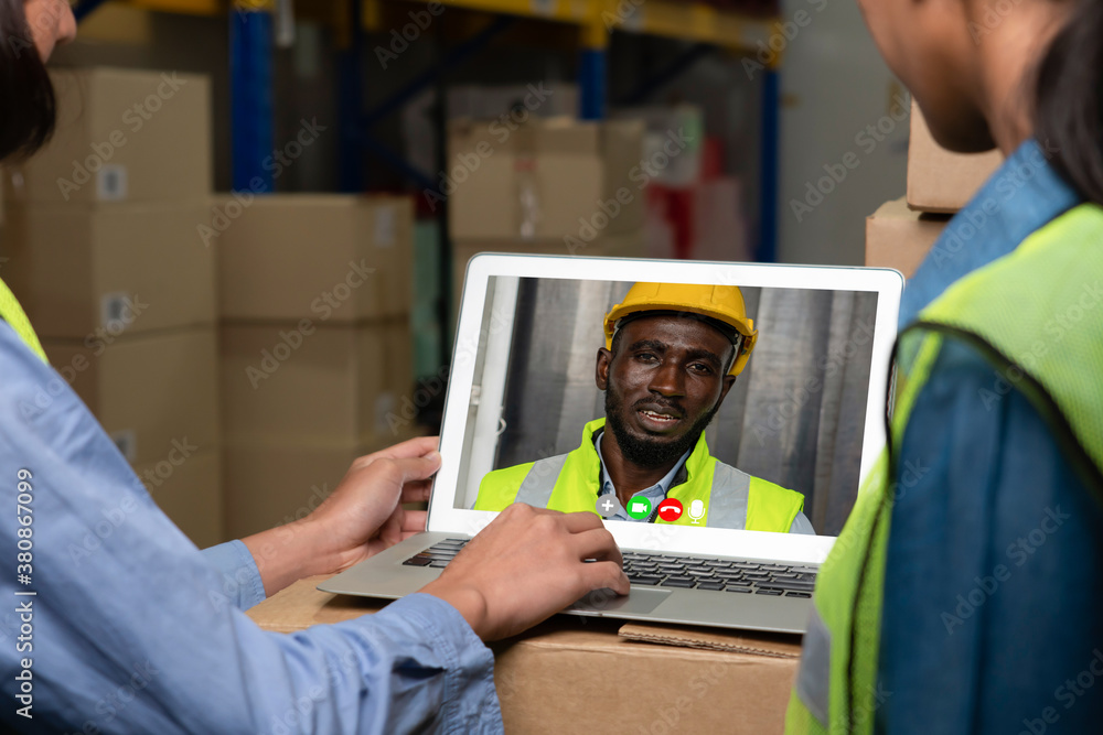 Warehouse staff talking on video call at computer screen in storage warehouse . Online software tech