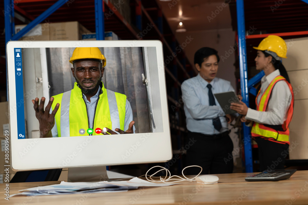 Warehouse staff talking on video call at computer screen in storage warehouse . Online software tech