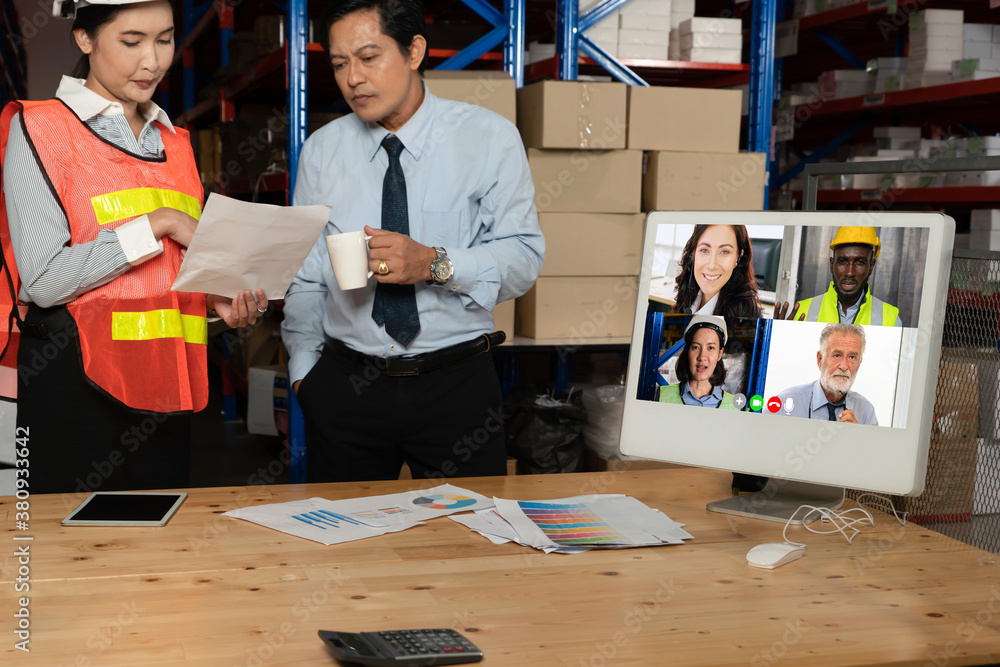 Warehouse staff talking on video call at computer screen in storage warehouse . Online software tech