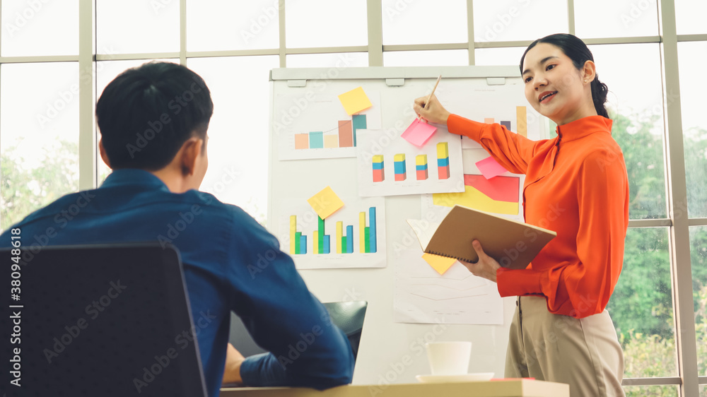 Young woman explains business data on white board in casual office room . The confident Asian busine