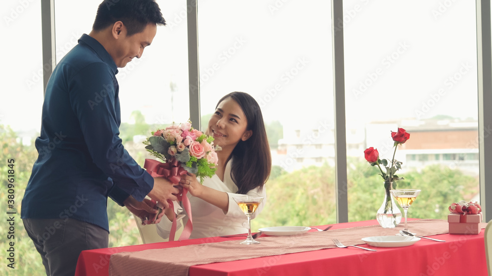 Romantic couple giving gift to lover at restaurant . Happy couple lifestyle .