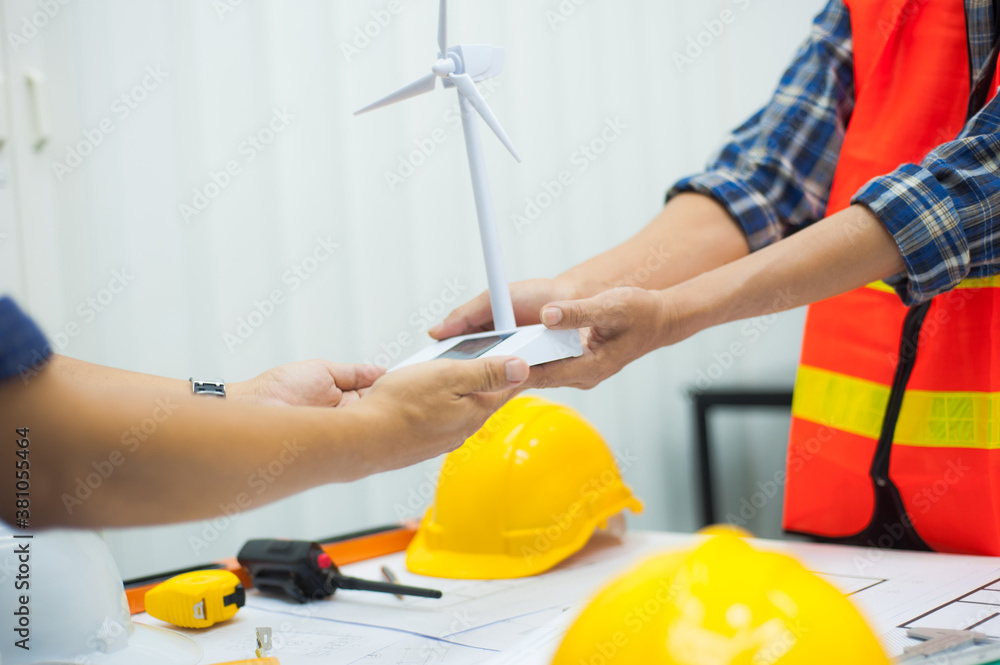 Engineer and assistant build a model of wind turbines to generate electricity.