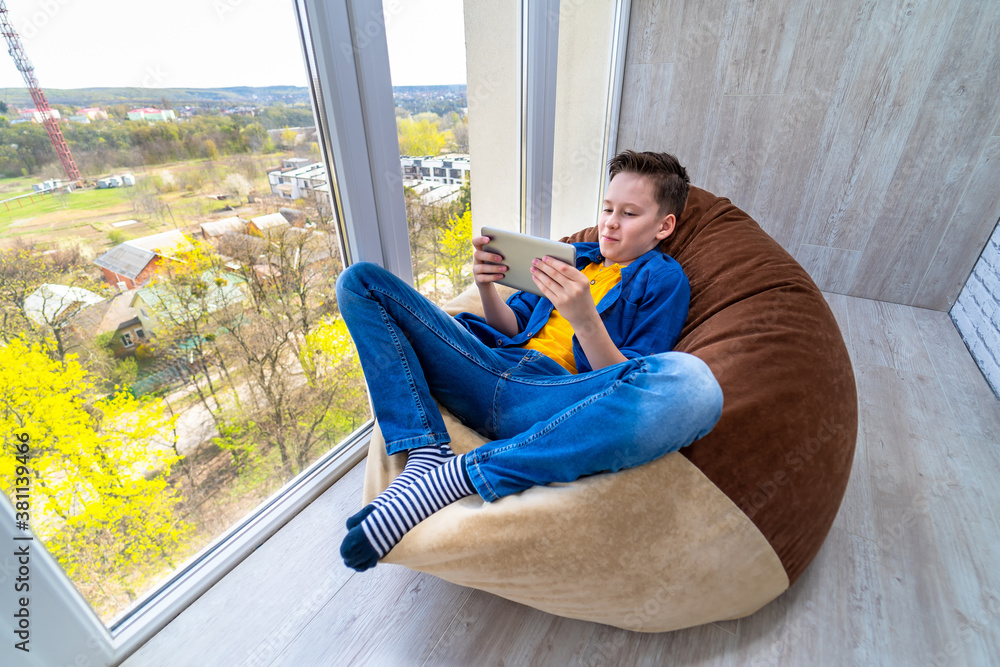 Little boy relaxing on a terrace and surfing the net on smart phone.