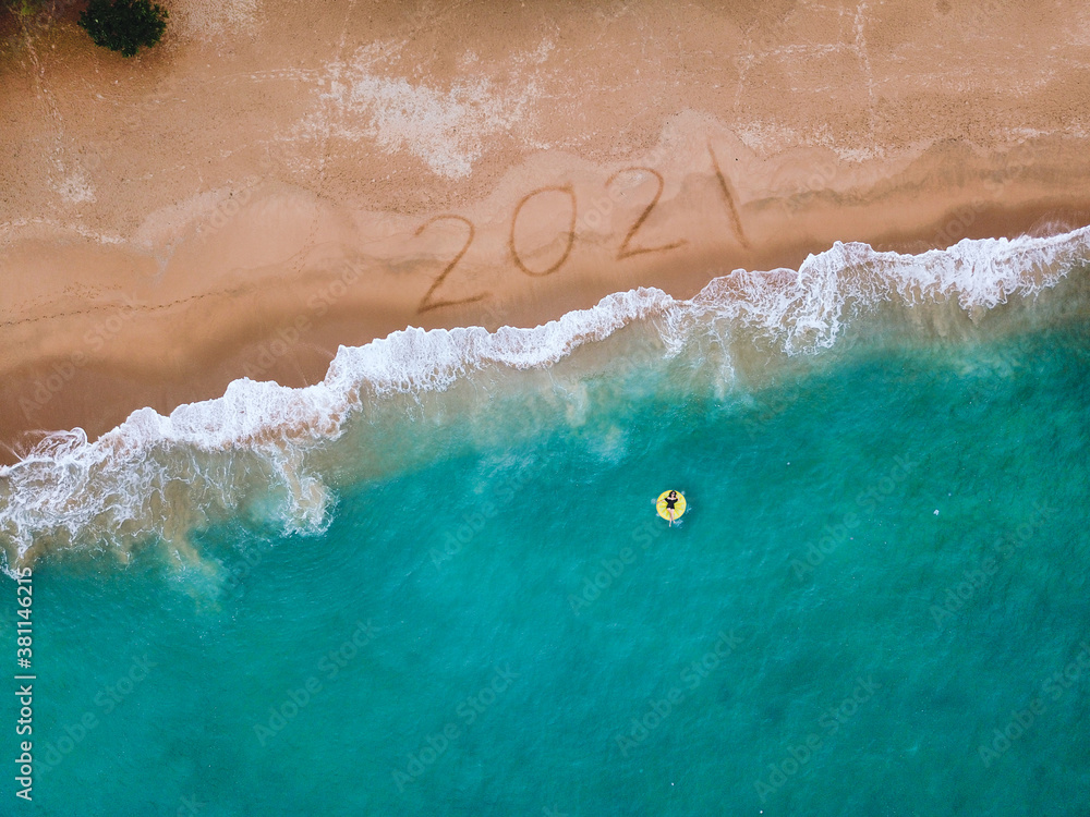 Happy New Year 2021, lettering on the beach with wave and blue sea. Numbers 2021 year on the sea sho