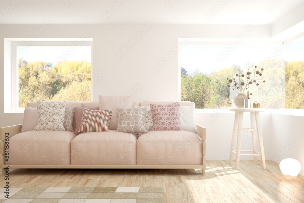 Stylish room in white color with sofa and autumn landscape in window. Scandinavian interior design. 