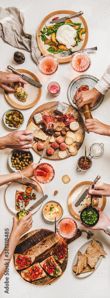 Family wine and snack party. Flay-lay of peoples hands eating and drinking rose wine over table with