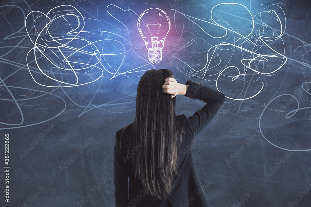 Businesswoman in suit looking on drawing  light bulb blackboard