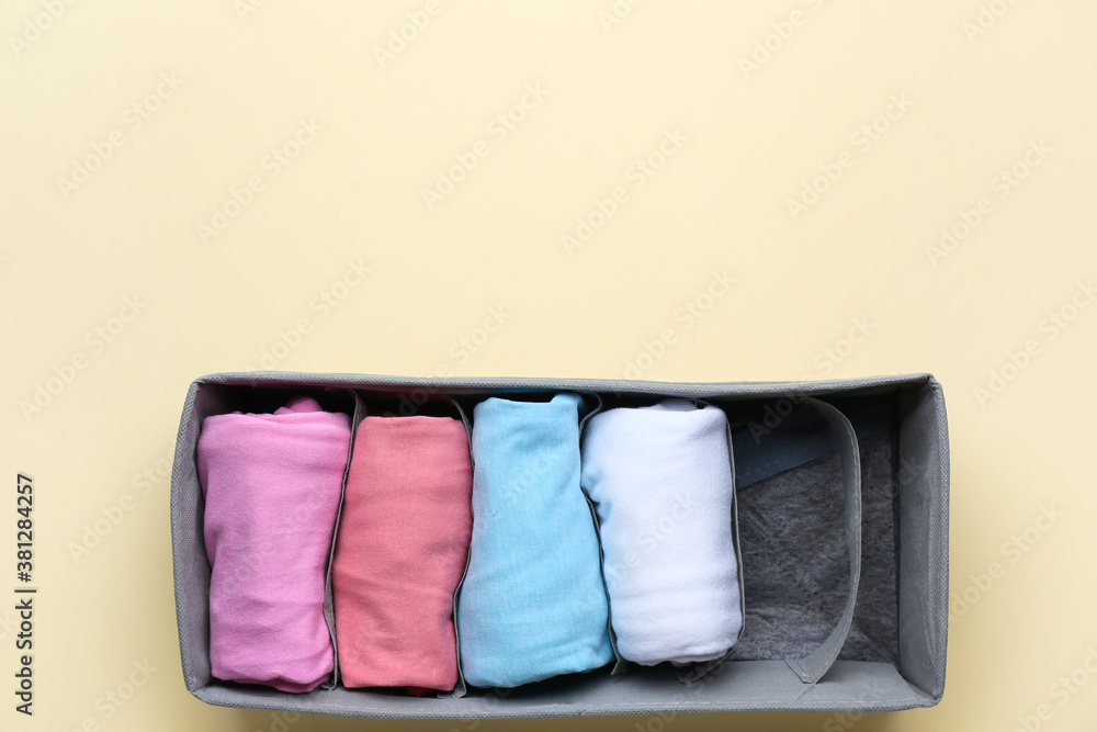 Organizer with clean clothes on color background