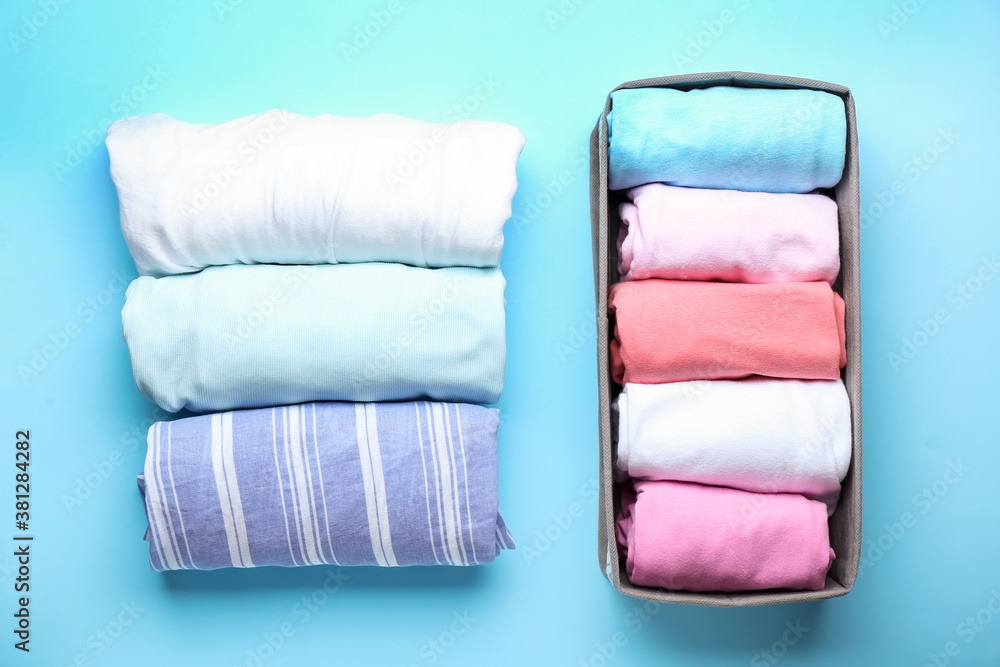 Organizer with clean clothes on color background