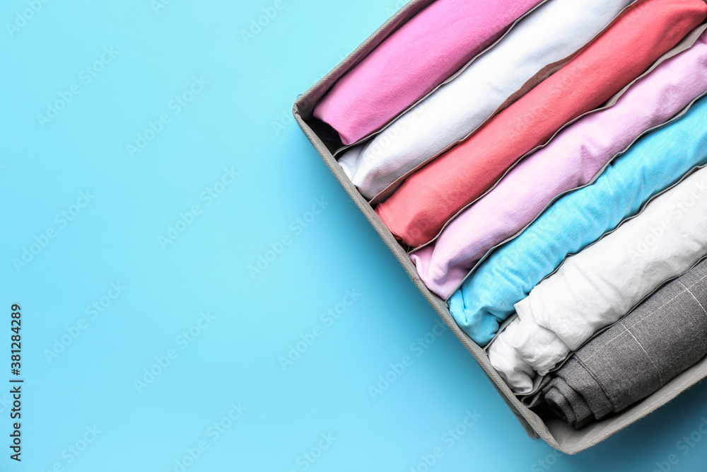 Organizer with clean clothes on color background