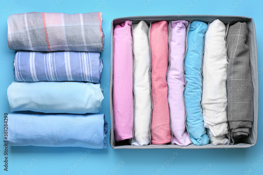 Organizer with clean clothes on color background