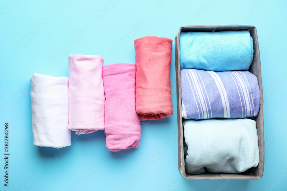 Organizer with clean clothes on color background