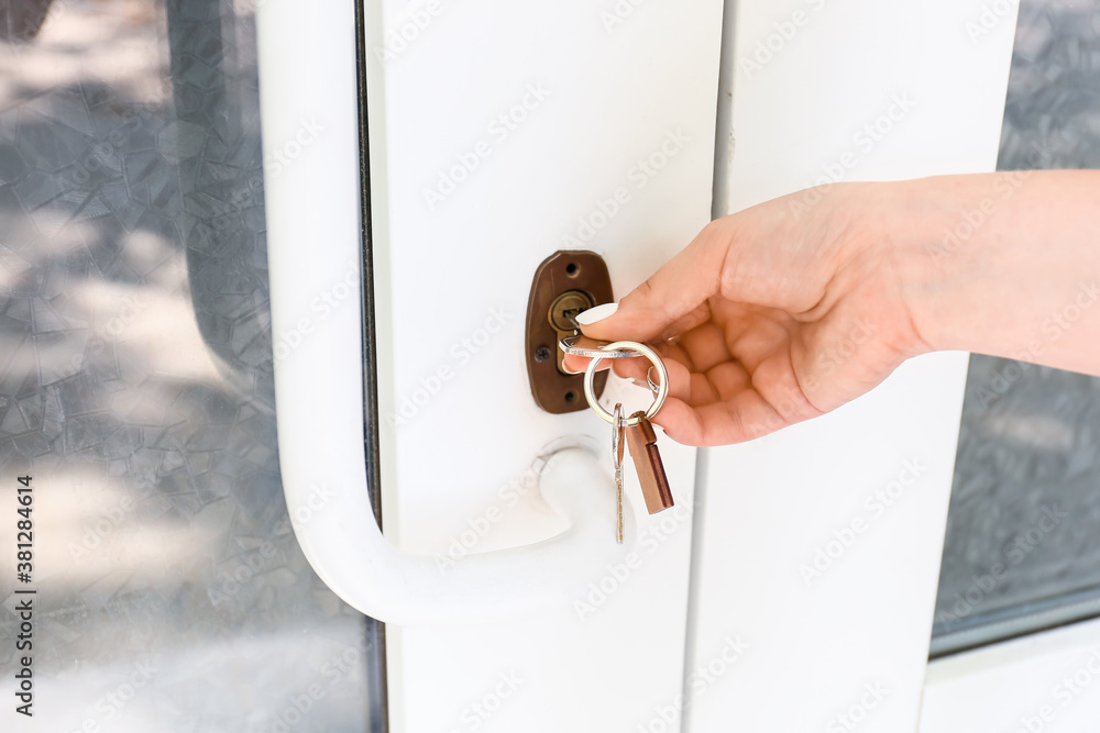 Woman using key to open door outdoors