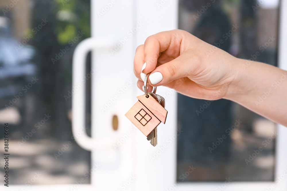 Woman with keys from house near door outdoors