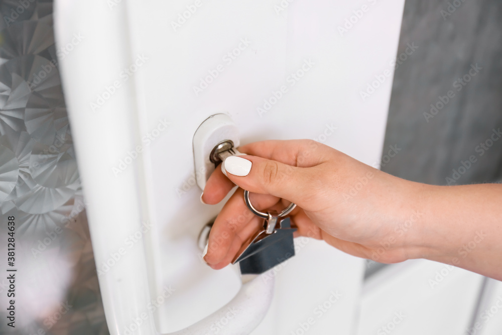 Woman using key to open door outdoors