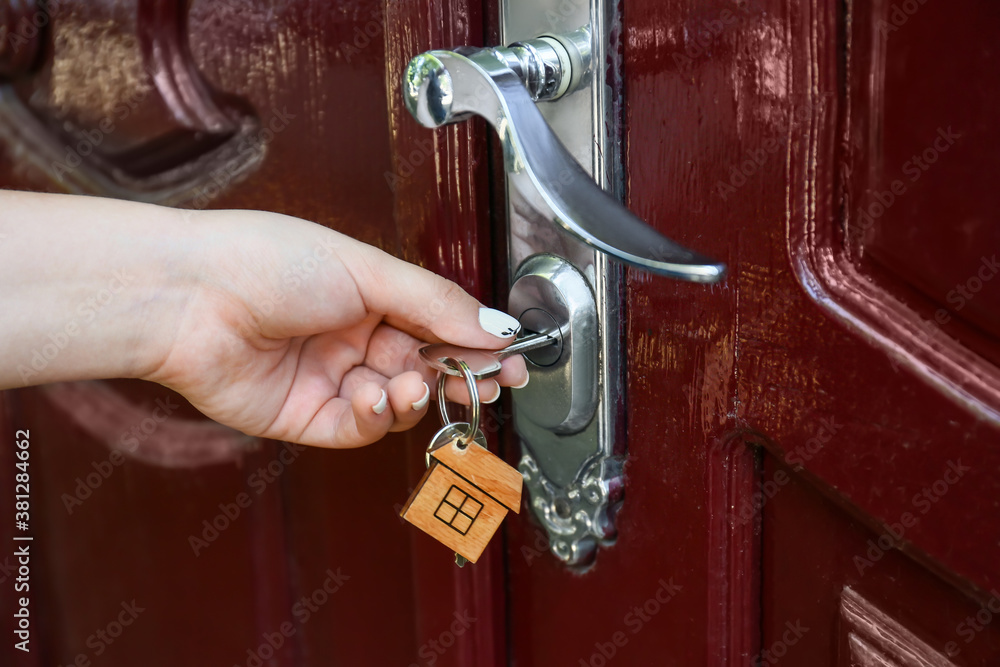 Woman using key to open door outdoors