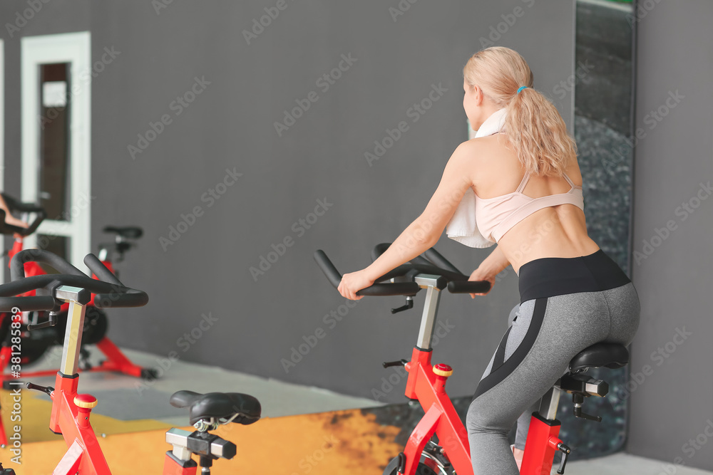 Young woman training on exercising bike in gym