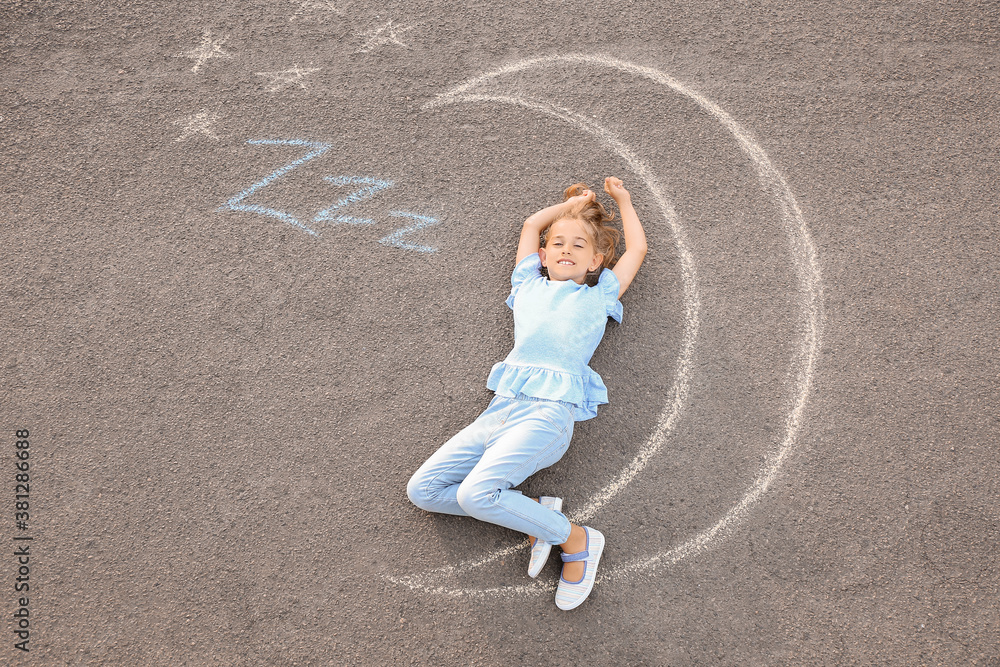 Little girl lying near chalk drawing of moon outdoors