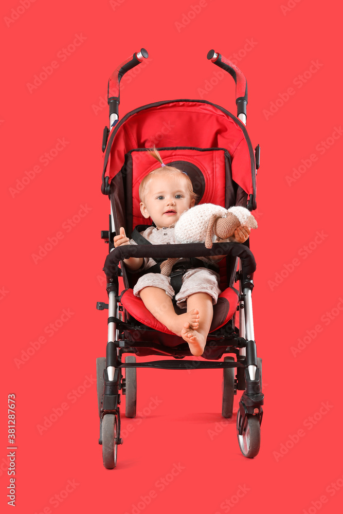 Cute little baby in stroller on color background