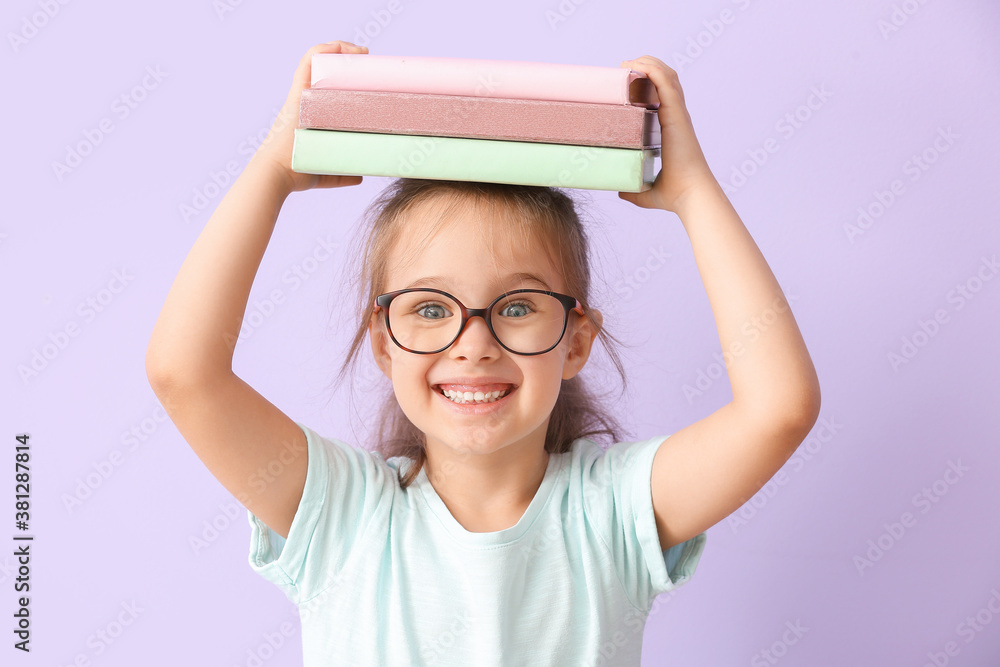 Little schoolgirl with books on color background