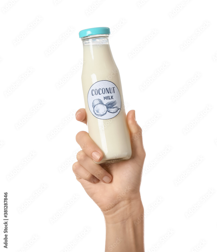 Female hand with bottle of coconut milk on white background