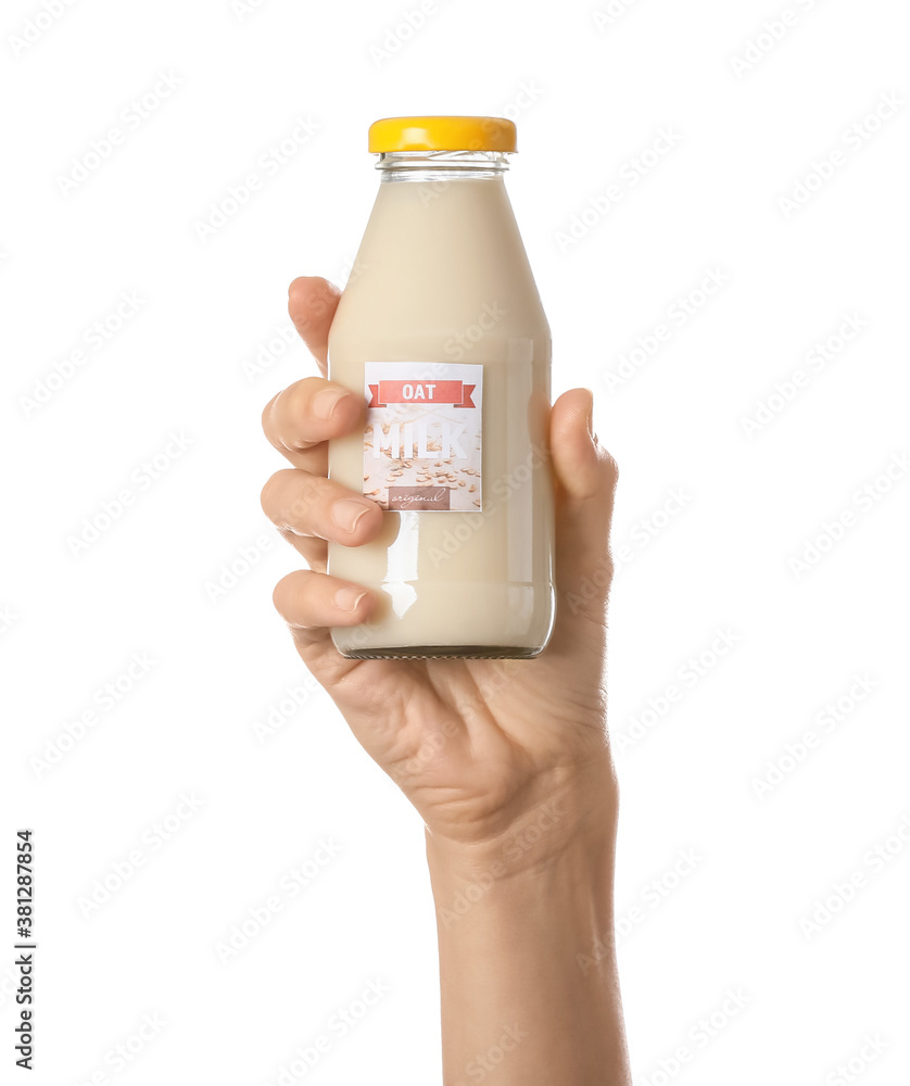 Female hand with bottle of oat milk on white background