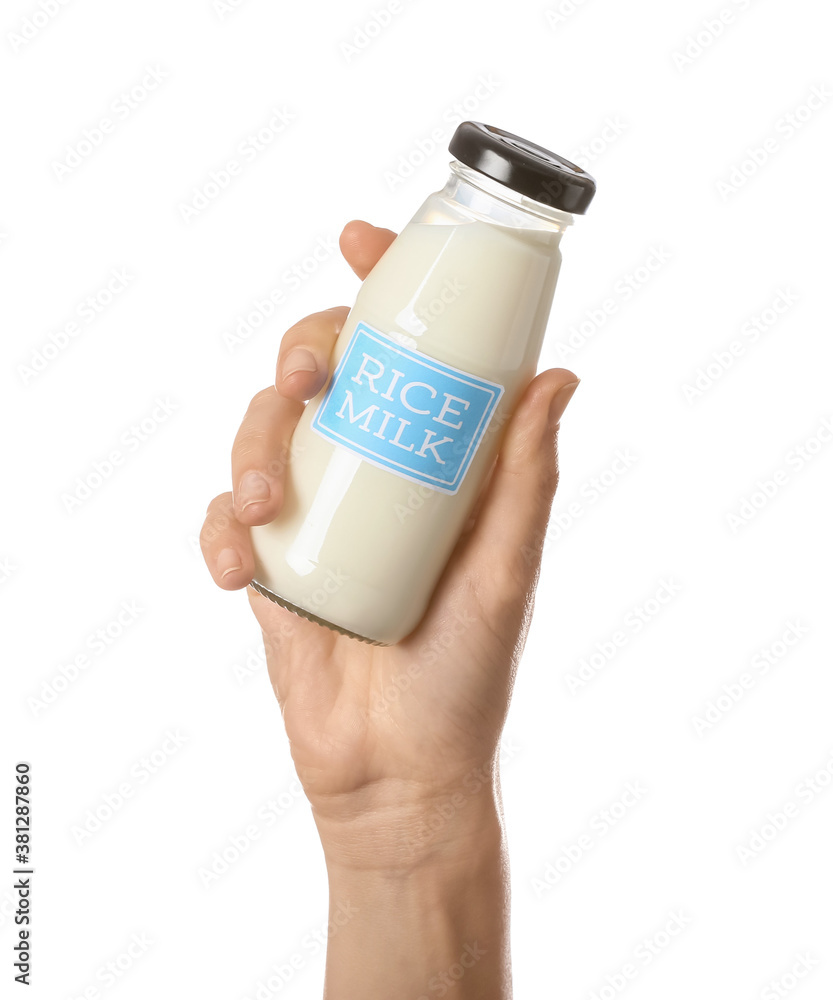 Female hand with bottle of rice milk on white background