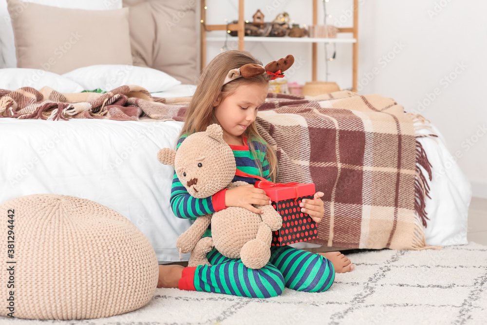 Cute little girl with Christmas gift at home