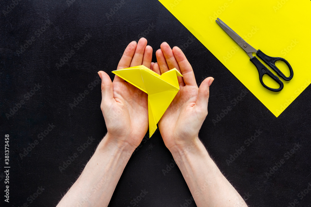 Origami bird in female hands. Care peace concept. Top view