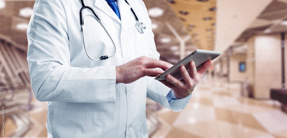 Doctor in white coat holding a digital tablet