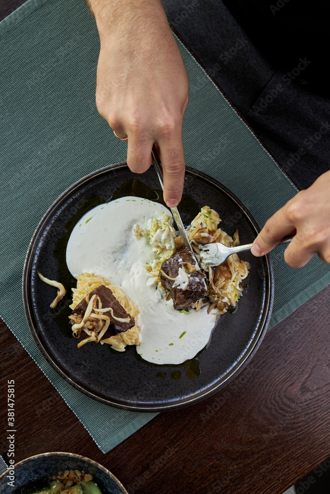 Person holds a fork in his food