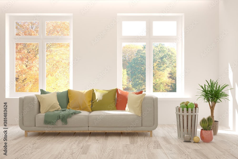 Stylish room in white color with sofa and autumn landscape in window. Scandinavian interior design. 