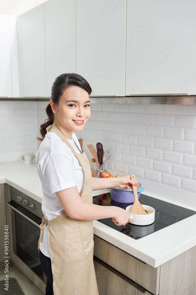 young attractive asian woman cooks in a kitchen,saute