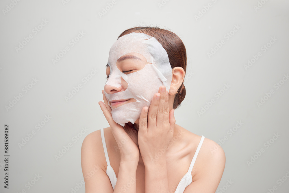 Young girl with facial mask looking at camera over white background. Cosmetic procedure. Beauty spa 