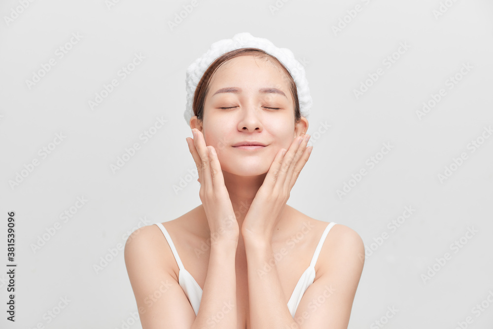 Happy young girl with clean skin and with a white towel on her head washes face