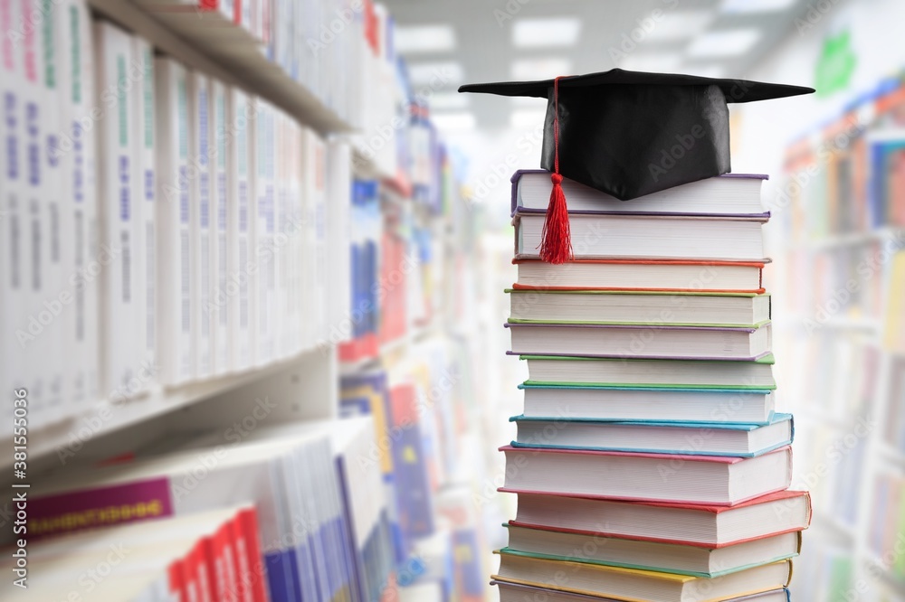 Stack school books with black graduation hat