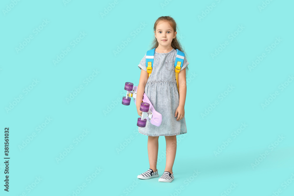 Little schoolgirl with skateboard on color background