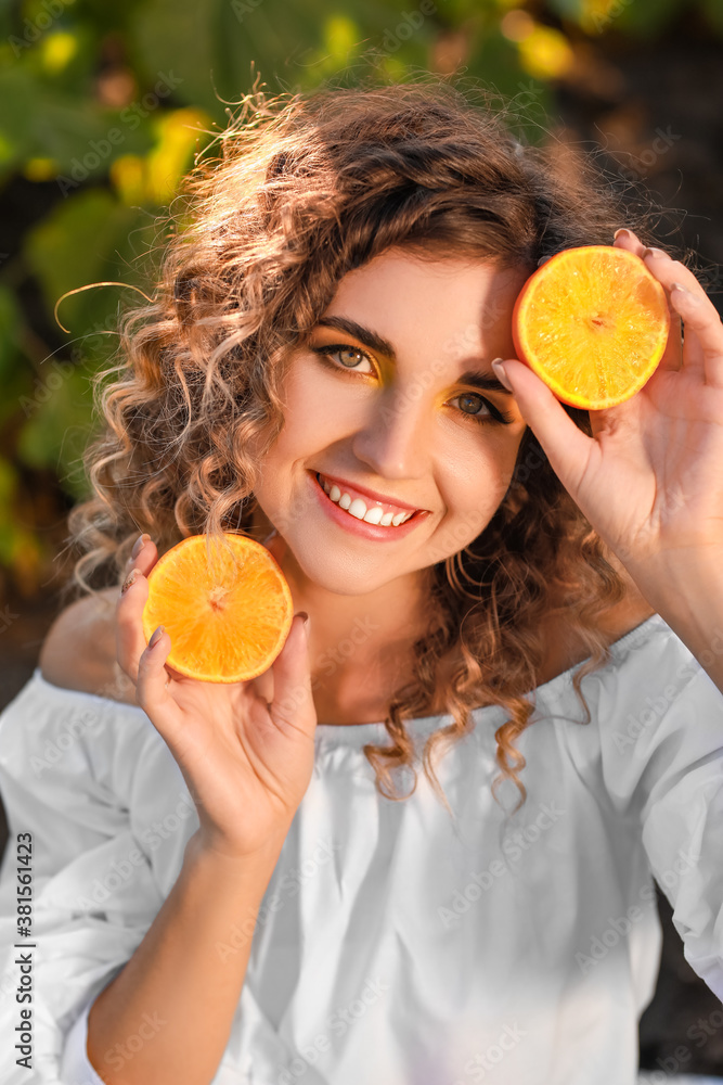 Beautiful young woman with orange in sunflower field