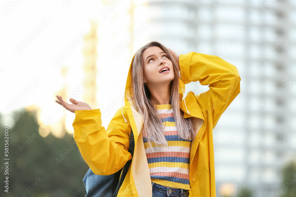 Beautiful young woman wearing raincoat outdoors