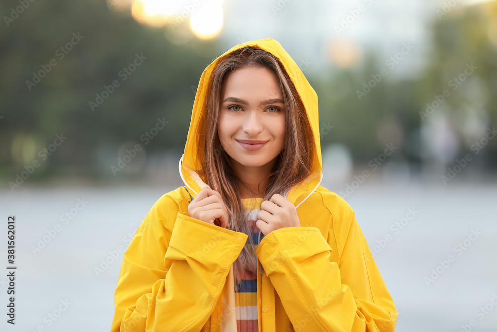 Beautiful young woman wearing raincoat outdoors