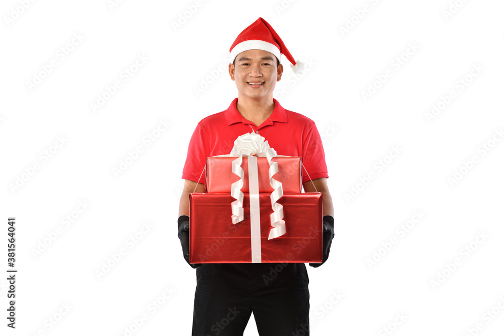 Happy young Asian delivery man in red uniform, Christmas hat carry boxes of presents in hands isolat