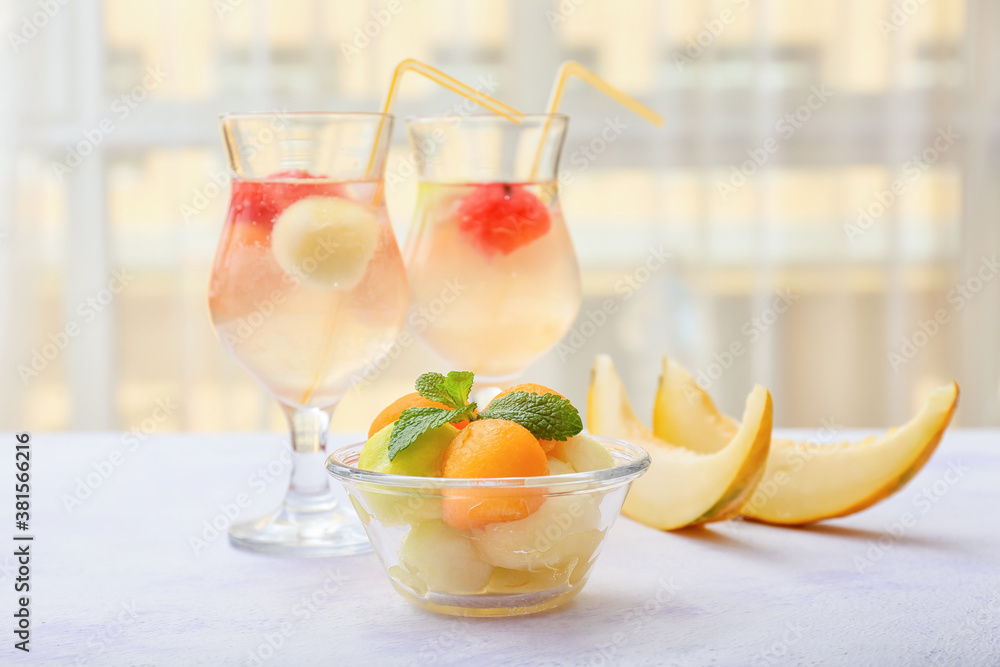 Tasty melon balls with cold cocktail on table