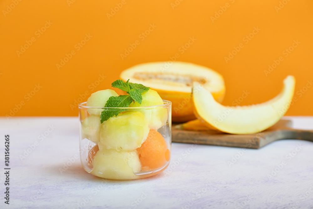 Glass with tasty melon balls on table