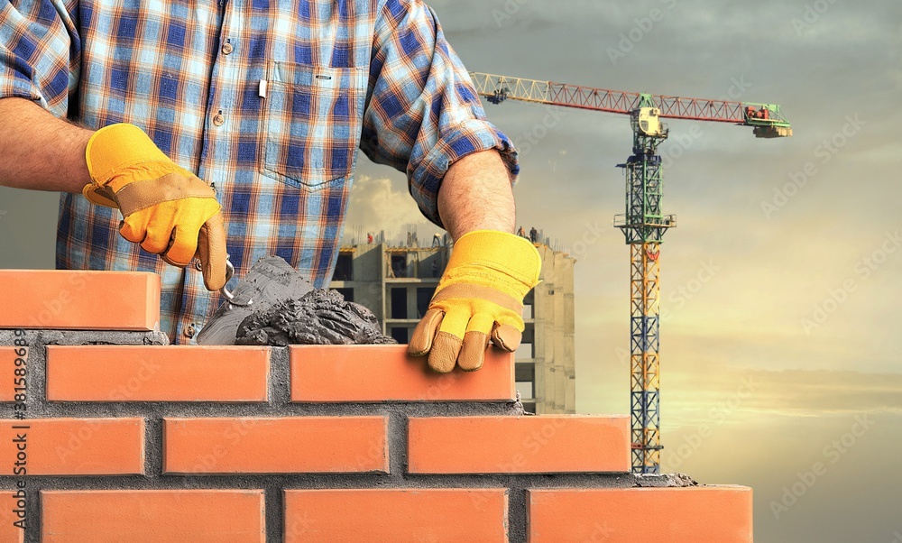 Bricklayer worker installing brick masonry