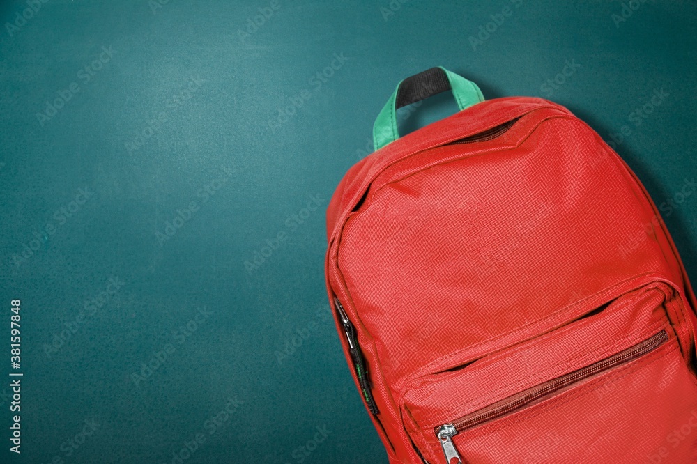 Red backpack with school supplies on background