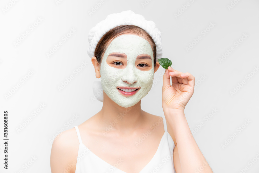 Portrait beautiful Asian woman in towel on head applying white nourishing mask or creme on face, gre