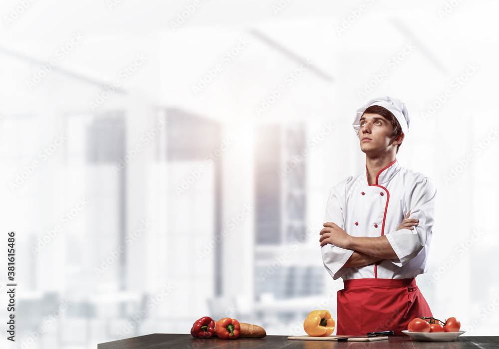 Young male chef standing with folded arms