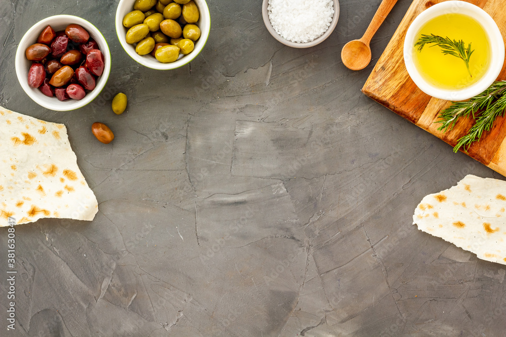 Mediterranean olives near bread on cutting board top view copy space