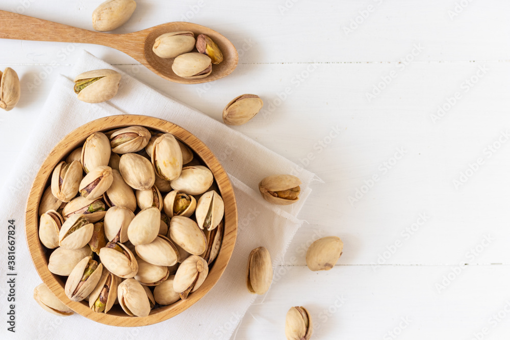 Top view of Pistachio nuts in a wooden bowl on white background