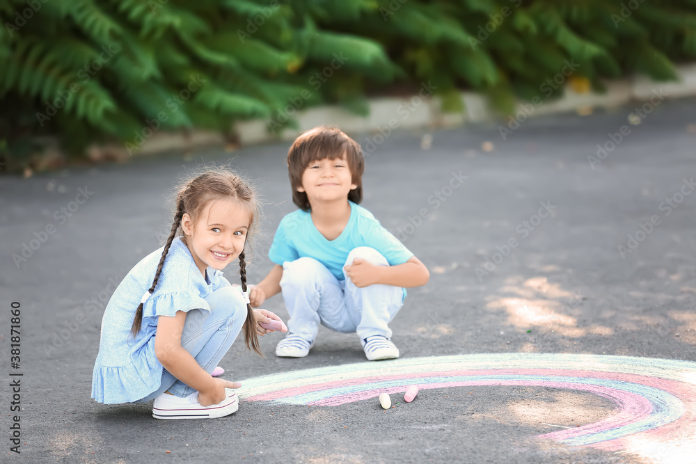 Little children drawing with chalk on asphalt